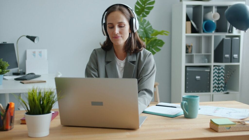 A lady works from home on her laptop using headphones, running her franchise business from home.